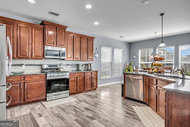 kitchen featuring recessed lighting, dark stone counters, decorative backsplash, stainless steel appliances, and a sink