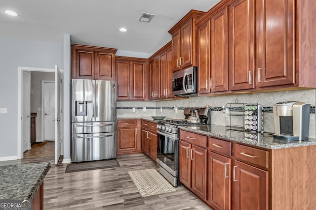 kitchen featuring dark stone counters, visible vents, stainless steel appliances, recessed lighting, and backsplash