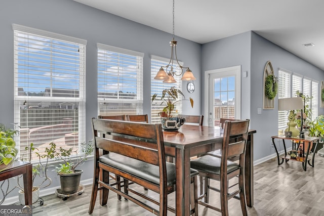 dining room featuring baseboards, wood finished floors, and an inviting chandelier