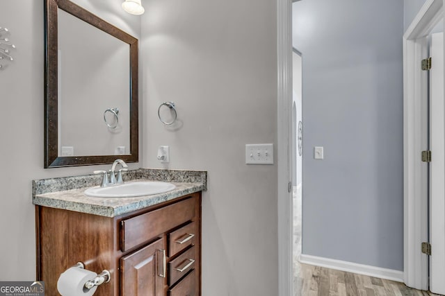 bathroom with wood finished floors, vanity, and baseboards