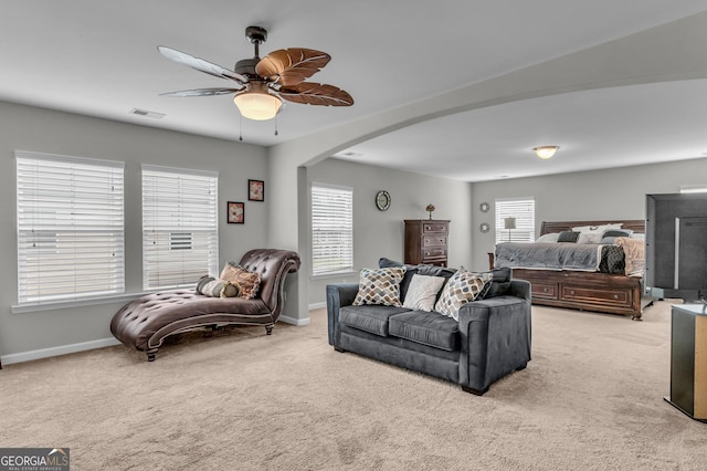 living room featuring arched walkways, visible vents, light colored carpet, and baseboards