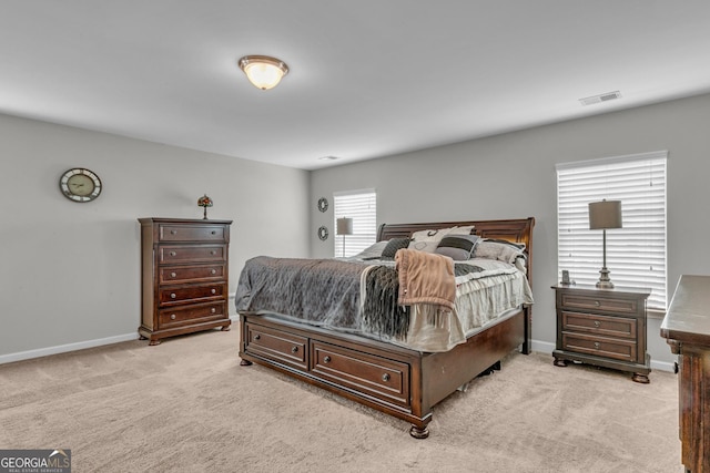 bedroom with baseboards, visible vents, and light colored carpet