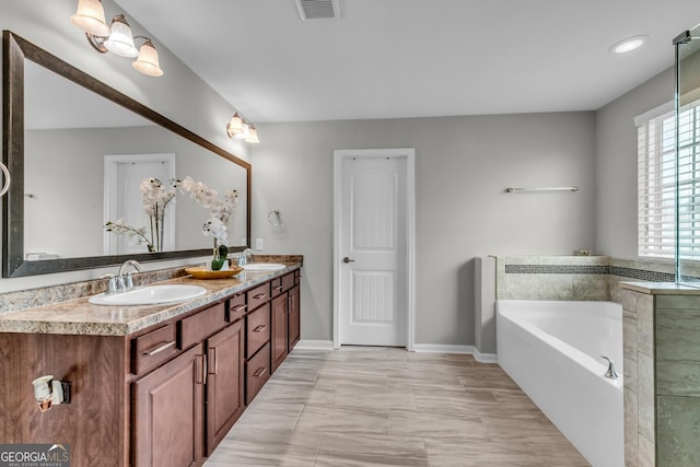 full bathroom with a sink, a garden tub, visible vents, and double vanity