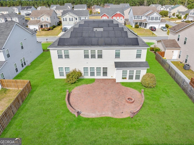 back of property with a fenced backyard, a residential view, and roof mounted solar panels