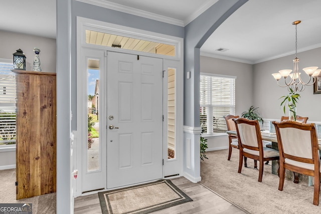 foyer featuring light wood-style flooring, a chandelier, visible vents, baseboards, and arched walkways