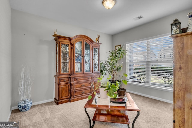 living area featuring carpet flooring, visible vents, baseboards, and a healthy amount of sunlight