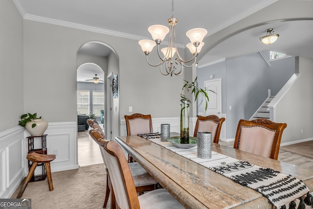 dining room featuring ornamental molding, arched walkways, a notable chandelier, and wainscoting