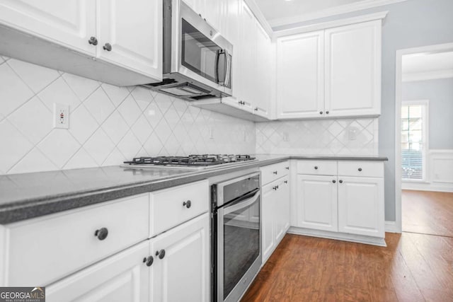 4522 Willow Oak Trl, Powder Springs, GA 30127 - kitchen with dark wood finished floors, white cabinetry, crown molding, and stainless steel appliances