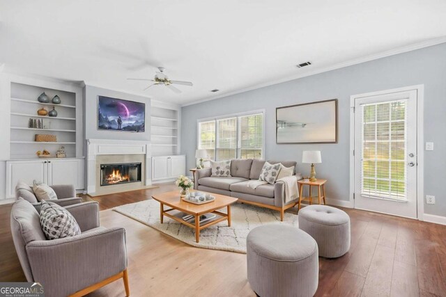 4522 Willow Oak Trl, Powder Springs, GA 30127 - living room with hardwood / wood-style flooring, built in shelves, a fireplace with flush hearth, a ceiling fan, and visible vents