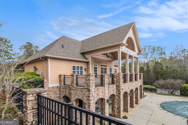 7497 Treehouse Ct, Douglasville, GA 30135 - view of side of home with a balcony, stone siding, roof with shingles, a fenced in pool, and a ceiling fan