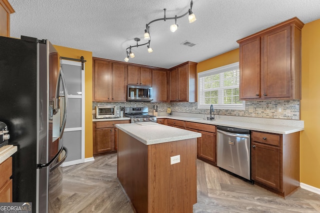 kitchen featuring visible vents, appliances with stainless steel finishes, a sink, light countertops, and a toaster