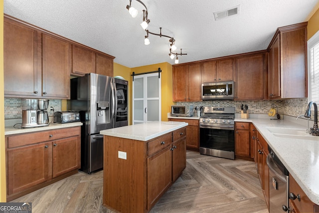 kitchen with a sink, stainless steel appliances, backsplash, a kitchen island, and visible vents