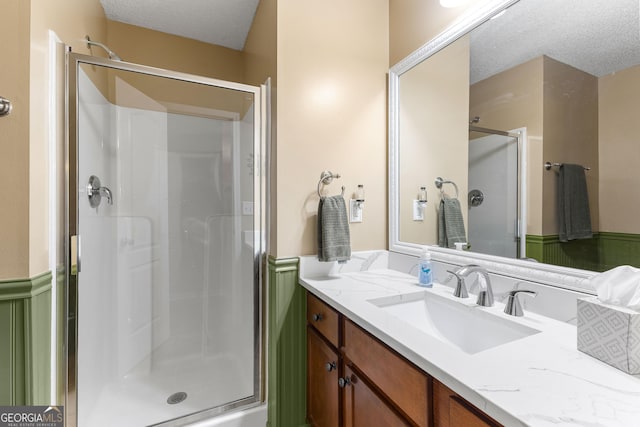 bathroom featuring vanity, a shower stall, and a textured ceiling