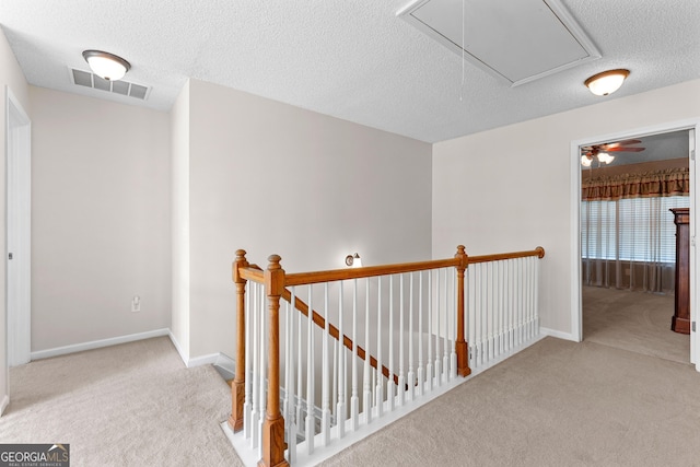 hallway featuring visible vents, an upstairs landing, carpet, and attic access