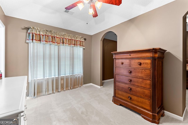 bedroom with visible vents, a ceiling fan, baseboards, light colored carpet, and arched walkways