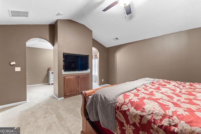 bedroom featuring a textured ceiling, visible vents, arched walkways, vaulted ceiling, and light carpet