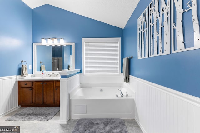 full bathroom with a bath, wainscoting, vanity, lofted ceiling, and a decorative wall