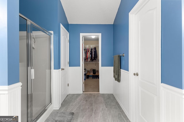 368 Yellowwood Dr, Sharpsburg, GA 30277 - bathroom with a stall shower, a wainscoted wall, a walk in closet, a decorative wall, and a textured ceiling