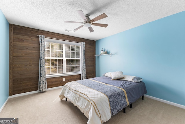 bedroom with wood walls, visible vents, baseboards, and carpet