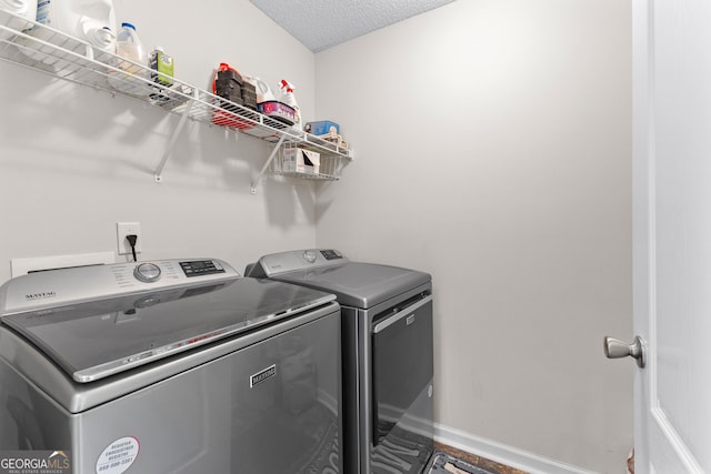 laundry room with a textured ceiling, laundry area, washing machine and dryer, and baseboards