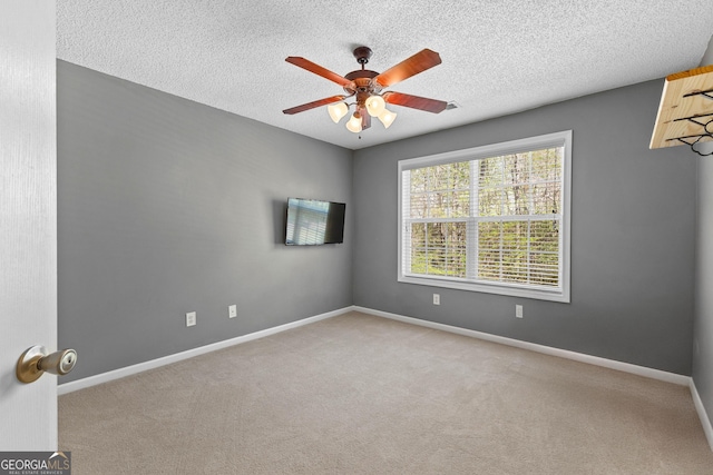 carpeted empty room with baseboards, a textured ceiling, and ceiling fan