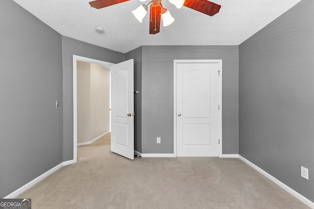 unfurnished bedroom with a textured ceiling, ceiling fan, baseboards, and carpet