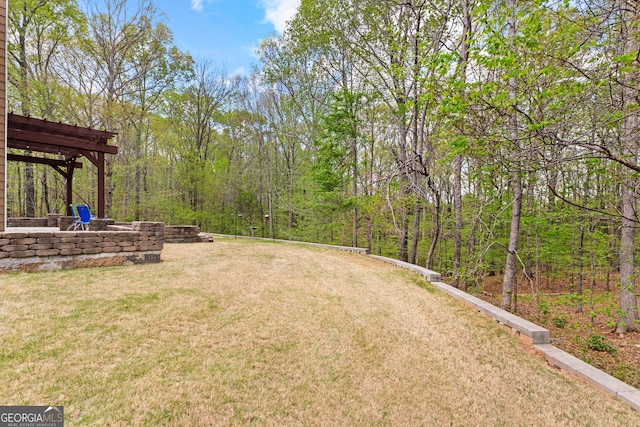 view of yard with a view of trees, an outdoor fire pit, and a pergola
