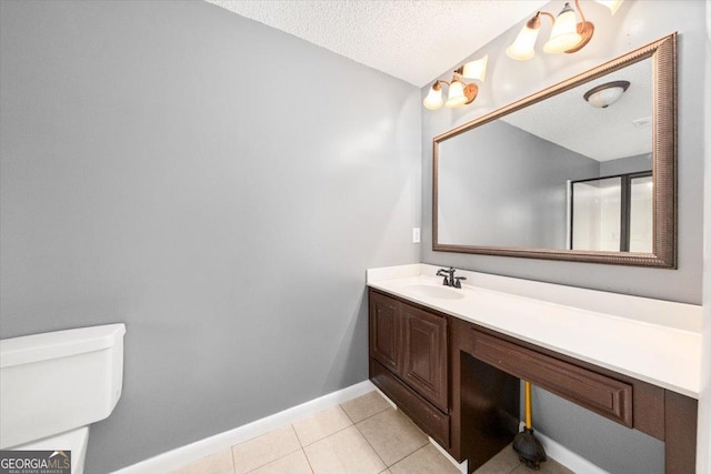 bathroom with tile patterned flooring, vanity, toilet, baseboards, and a textured ceiling