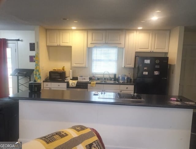 kitchen featuring a sink, white cabinetry, black appliances, and dark countertops