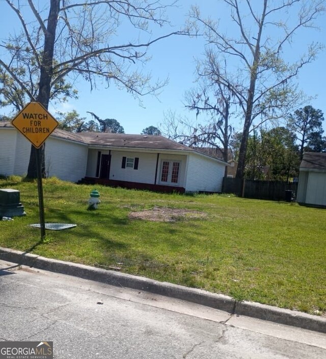 view of front of house featuring an outbuilding, a storage unit, french doors, and a front yard