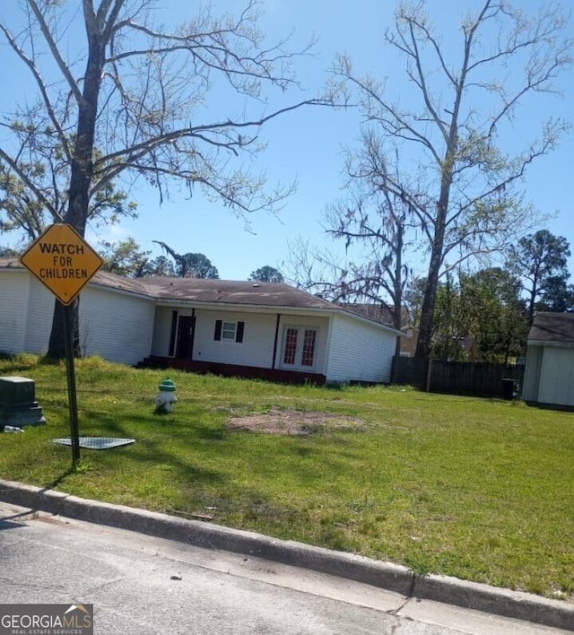 single story home with a storage unit, fence, a front yard, and an outdoor structure