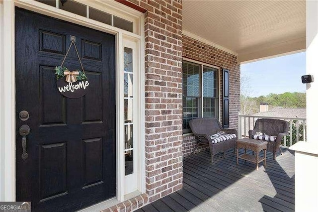 view of exterior entry featuring brick siding and a porch