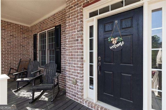 doorway to property featuring brick siding and a porch