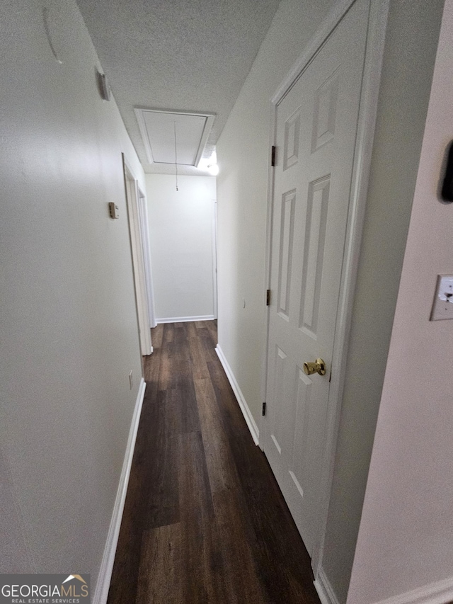 corridor featuring attic access, baseboards, and wood finished floors