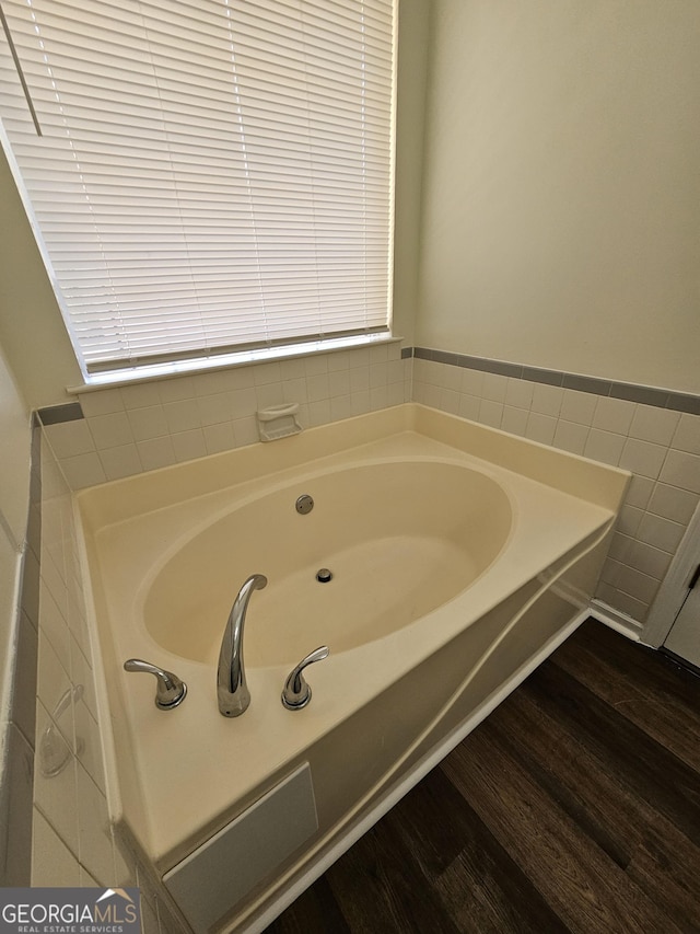 bathroom featuring wood finished floors, a garden tub, tile walls, and wainscoting
