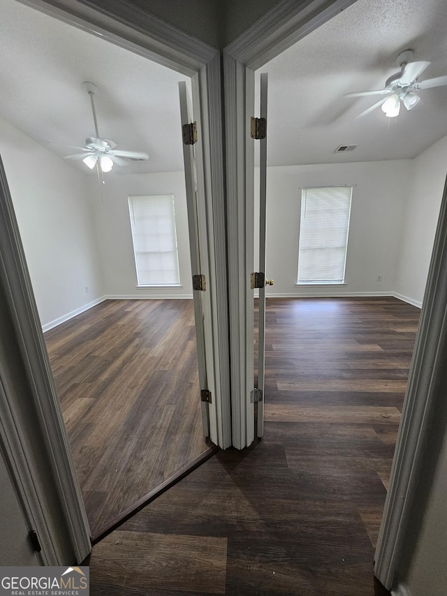 hallway featuring baseboards, visible vents, and dark wood finished floors