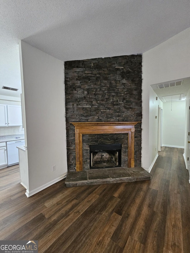 unfurnished living room featuring attic access, wood finished floors, visible vents, and a fireplace