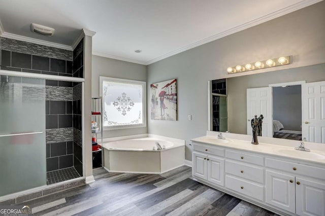 ensuite bathroom featuring a sink, crown molding, a stall shower, and a bath