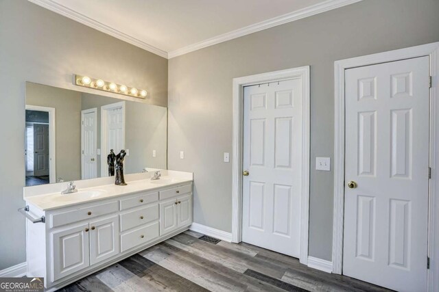 full bathroom with crown molding, a sink, wood finished floors, baseboards, and double vanity