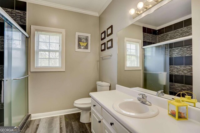 bathroom with toilet, crown molding, a stall shower, and wood finished floors