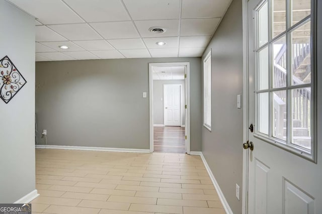 interior space with a drop ceiling, recessed lighting, baseboards, and visible vents