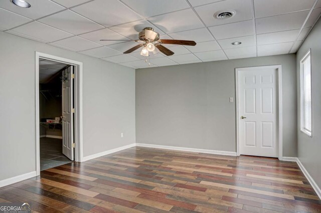 unfurnished bedroom featuring baseboards, visible vents, a drop ceiling, and wood finished floors