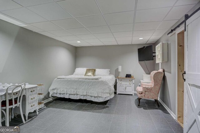 bedroom featuring baseboards, a barn door, recessed lighting, and a drop ceiling