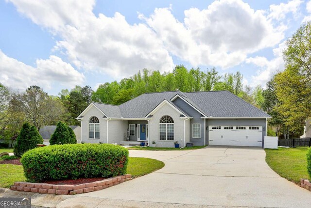 single story home featuring fence, driveway, a front lawn, brick siding, and a garage