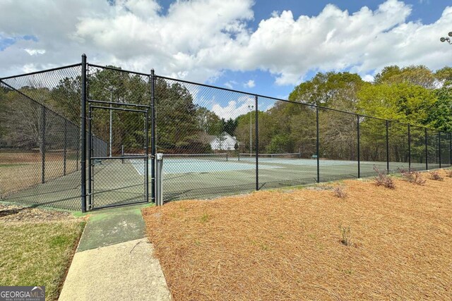 view of tennis court featuring a gate and fence