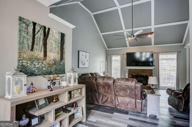 living area with vaulted ceiling, crown molding, a fireplace, wood finished floors, and ceiling fan