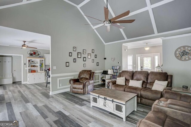 living area featuring a ceiling fan, ornamental molding, high vaulted ceiling, and light wood-type flooring