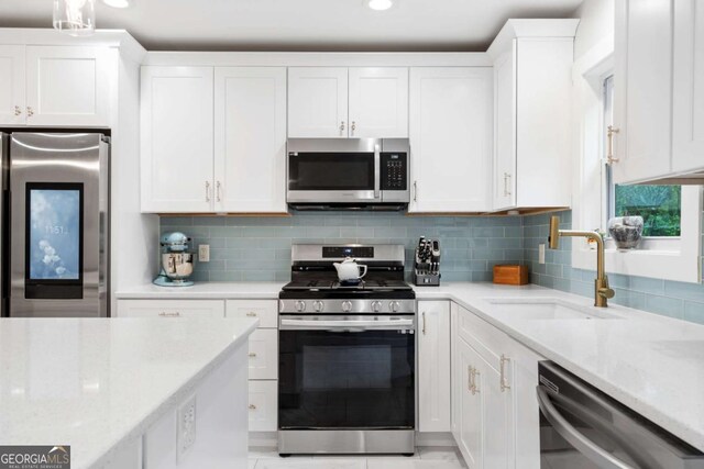 kitchen featuring white cabinetry, a sink, stainless steel appliances, and tasteful backsplash