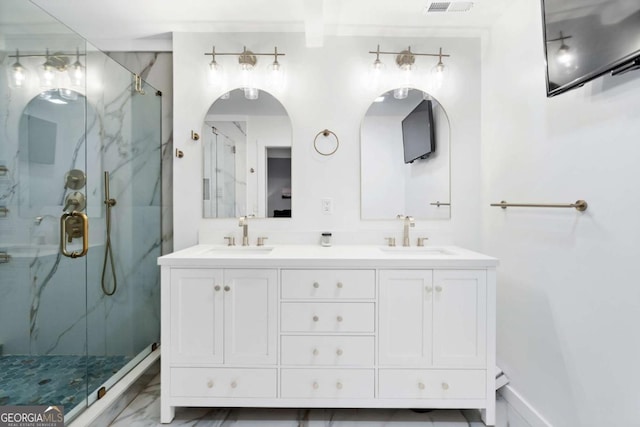 full bath with marble finish floor, a sink, a marble finish shower, and double vanity