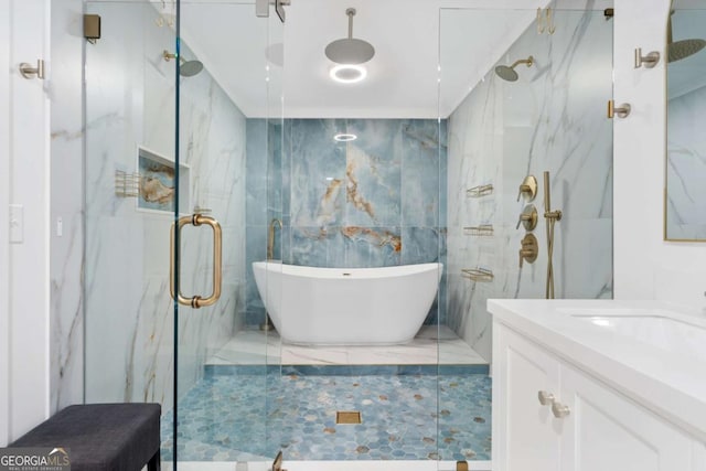 full bath featuring a freestanding bath, vanity, a marble finish shower, and tile walls